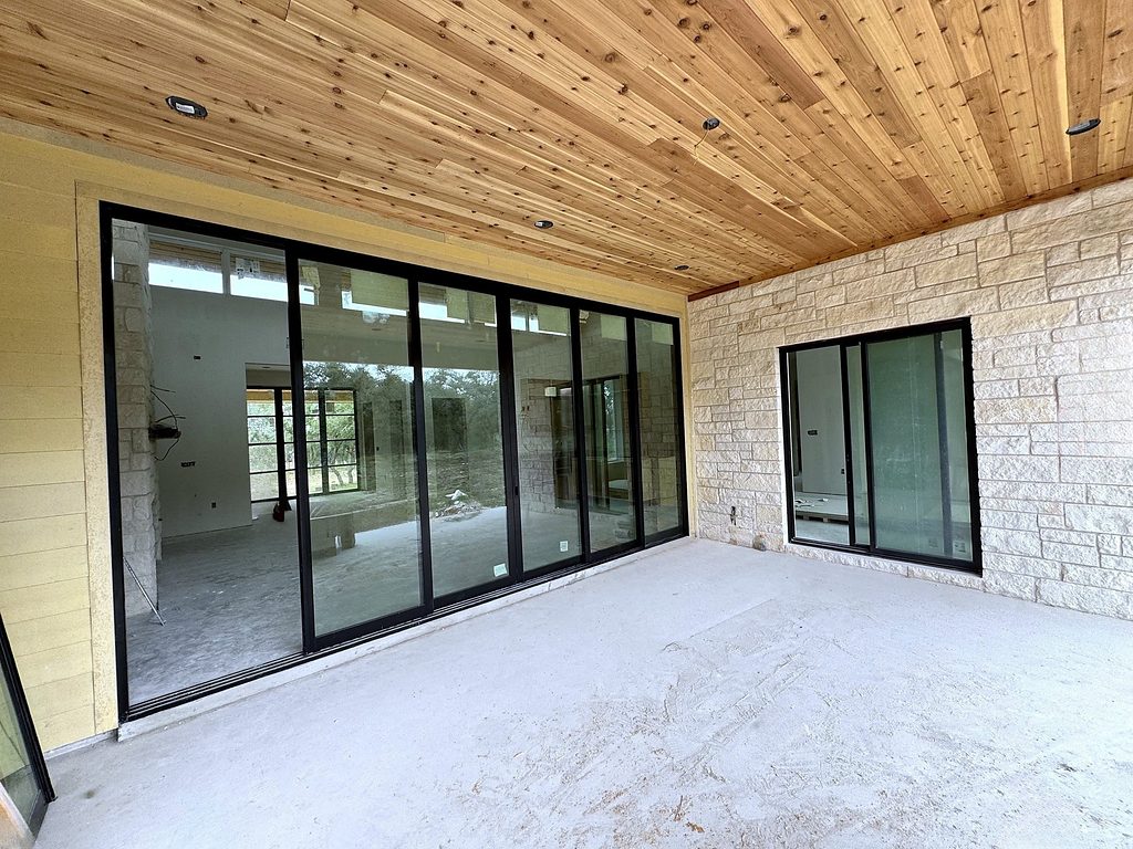 Real photo of the covered back porch with cedar tongue-and-groove ceiling and wide black-framed sliding doors at 168 Crooked Creek Court, October 2026