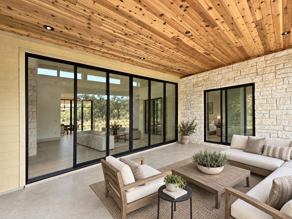 Conceptual rendering of the 168 Crooked Creek covered patio with cedar ceiling, limestone wall and wide black-framed sliding doors, Johnson City, TX