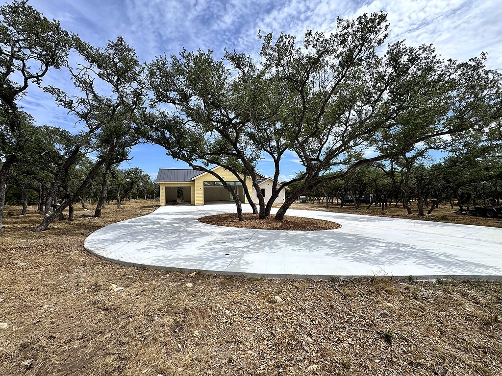 Real photo of the driveway loop around a live-oak island at 168 Crooked Creek Court, Johnson City, TX, September 2026