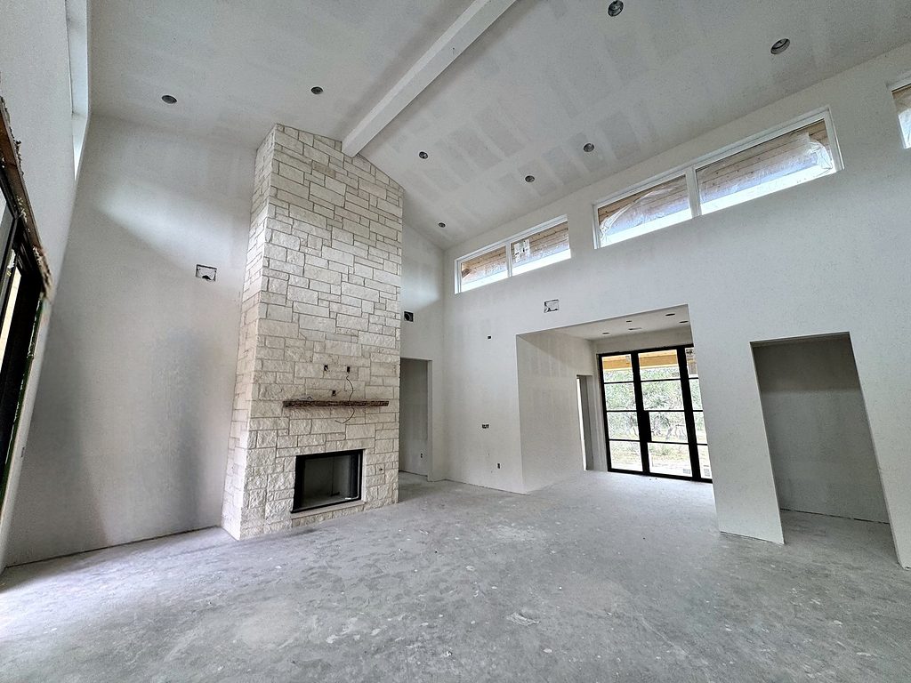 Real photo of the vaulted great room with floor-to-ceiling limestone fireplace and clerestory windows at 168 Crooked Creek Court, October 2026