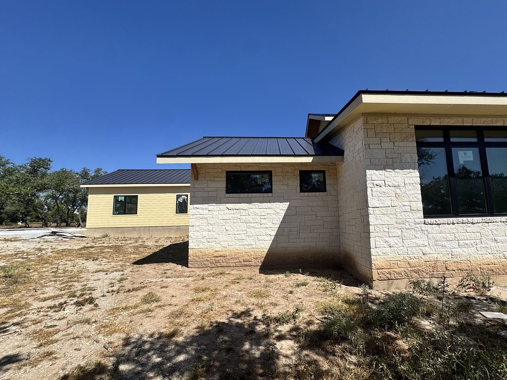 Real photo of the limestone veneer, painted lap siding and standing-seam metal roof at 168 Crooked Creek Court, September 2026